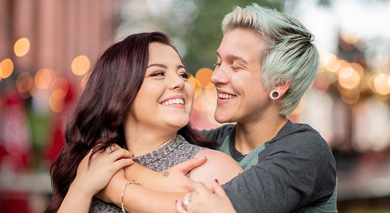 same-sex couple smiling and embracing one another